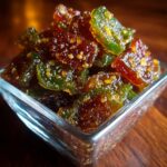 Mason jars of sweet cowboy candy candied jalapeños in glossy amber syrup with sliced peppers visible