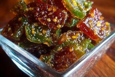 Mason jars of sweet cowboy candy candied jalapeños in glossy amber syrup with sliced peppers visible