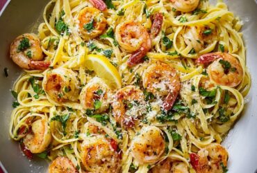 Shrimp linguine with garlic butter sauce, parsley, and lemon wedges in a white bowl
