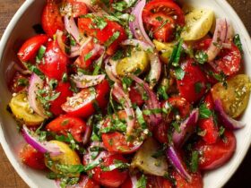 Tuscan tomato salad with heirloom tomatoes, cucumber, red onion, basil, and olives in a rustic bowl