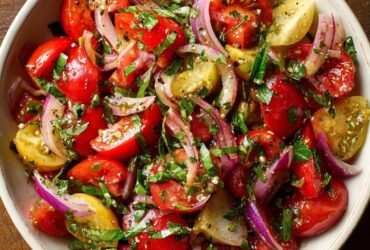 Tuscan tomato salad with heirloom tomatoes, cucumber, red onion, basil, and olives in a rustic bowl