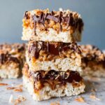 Samoa rice krispie treats squares topped with toasted coconut, caramel drizzle, and dark chocolate