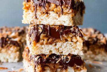 Samoa rice krispie treats squares topped with toasted coconut, caramel drizzle, and dark chocolate