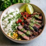 Cilantro lime steak bowl with sliced steak, cilantro lime rice, black beans, corn, avocado, and lime wedge