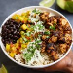 Cuban chicken and black bean rice bowl with cilantro lime rice, mojo-marinated chicken, plantains, and fresh cilantro