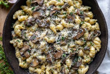 Creamy roasted garlic and mushroom pasta in a black skillet with fresh thyme, parmesan, and cracked pepper