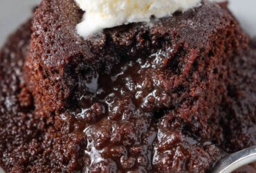Crockpot lava cake served warm with a molten chocolate center, vanilla ice cream scoop, and powdered sugar dusting