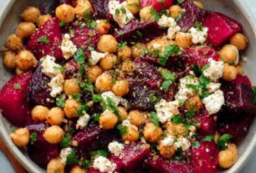Chickpea beet feta salad in a wooden bowl with vibrant pink-stained chickpeas, crumbled feta, fresh dill, and arugula