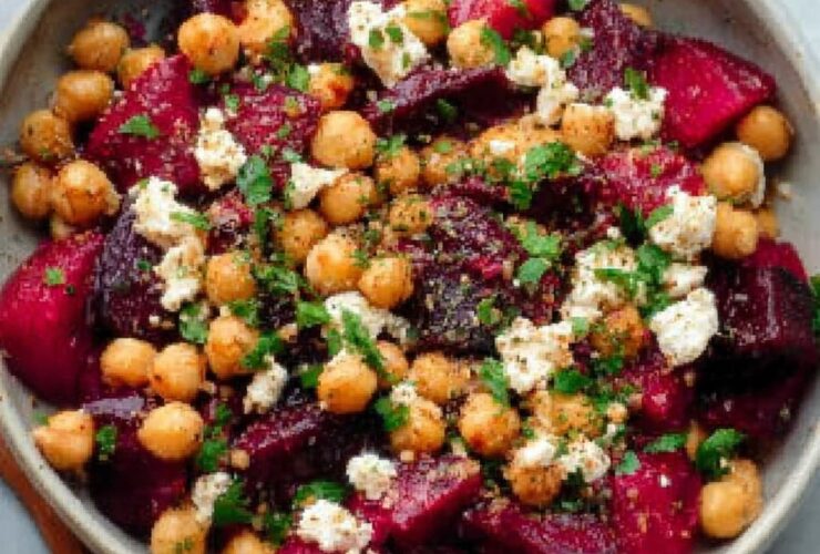 Chickpea beet feta salad in a wooden bowl with vibrant pink-stained chickpeas, crumbled feta, fresh dill, and arugula