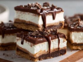 No-bake chocolate cream cheese bars cut into squares with chocolate cookie crust, fluffy cream cheese filling, and chocolate ganache top