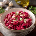 Hot pink beet sauce pasta with creamy roasted beet sauce coating fettuccine, topped with crumbled goat cheese, walnuts, and dill