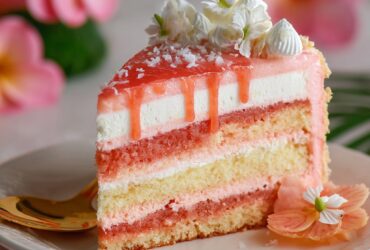 Hawaiian guava cake with vibrant pink layers, fluffy whipped cream cheese frosting, and glossy guava jelly glaze on top