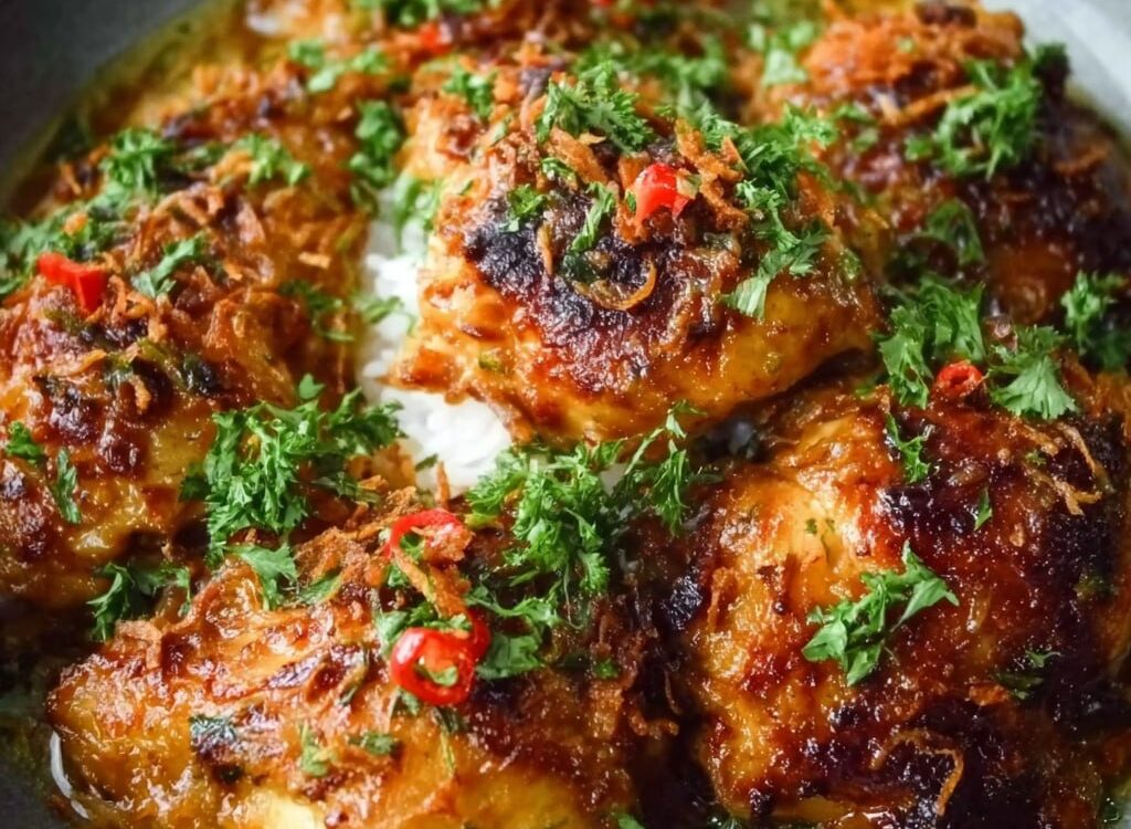 Indonesian coconut chicken with golden curry sauce, lemongrass, ginger, fresh basil, lime wedges, and jasmine rice on a plate