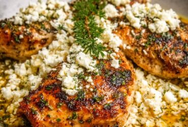 Greek chicken with lemon, feta, oregano, and olives in a sheet pan with golden crispy skin and bright Mediterranean colors