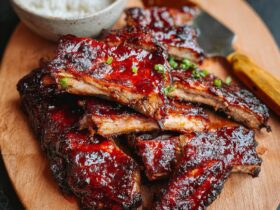 Chinese BBQ ribs with glossy red char siu glaze, sticky caramelized edges, sesame seeds, scallions, and steamed rice