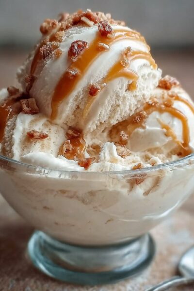 Bowl of high-protein salted caramel cottage cheese ice cream with caramel sauce drizzle, flaky sea salt, and chocolate chips on top