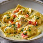 Lobster ravioli plated with bright lemon butter sauce, fresh chives, parmesan shavings, and lemon zest in a white bowl
