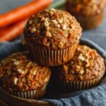 One-bowl carrot oatmeal muffins with golden tops, oat-cinnamon streusel, walnuts, and grated carrots visible in tender crumb