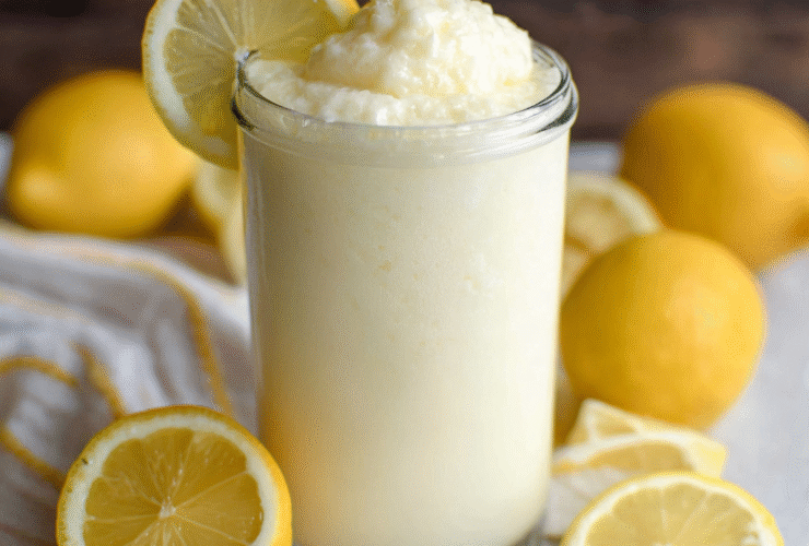 Chick-fil-A frosted lemonade copycat in a tall glass with thick creamy texture, lemon slice on the rim, pale yellow color, whipped cream on top
