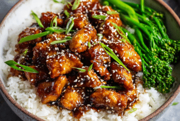 Healthy sesame chicken with glazed chicken pieces, sesame seeds, green onions, served over white rice with broccoli