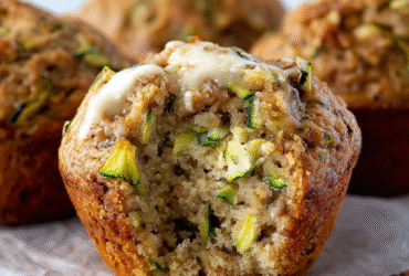 Banana zucchini muffins on a wooden board with golden tops, visible zucchini and banana, dusting of cinnamon sugar, walnuts