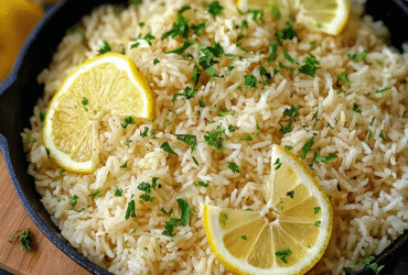 Greek lemon rice in a serving bowl with fluffy yellow rice, fresh dill, lemon zest, lemon wedges, olive oil drizzle