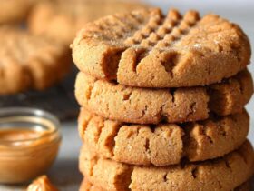 Peanut butter cookies on a wooden board with classic crosshatch fork pattern on top, golden edges, soft chewy centers, sea salt sprinkle