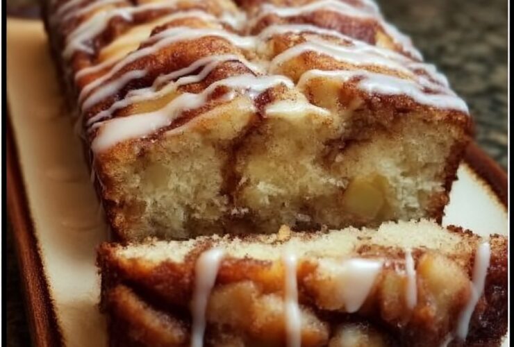 Cinnamon roll bread with icing on a wooden board, sliced loaf revealing soft cinnamon-sugar swirl, generous white vanilla icing drizzled across the top