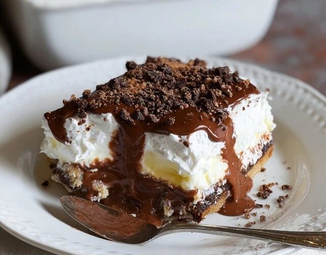 Chocolate lasagna dessert squares on a plate showing distinct layers of Oreo crust, cream cheese, chocolate pudding, whipped Cool Whip topping, chocolate shavings
