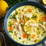 Lemon chicken soup in a white bowl with shredded chicken, orzo pasta, silky lemon-egg broth, lemon slices, fresh dill garnish, golden surface from emulsified egg