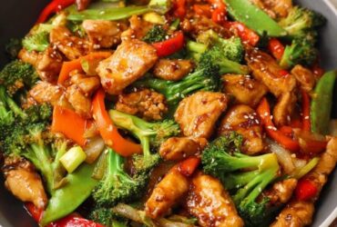 Chicken stir fry with vegetables in a wok, golden seared chicken pieces with bright bell peppers, broccoli florets, snap peas, glossy soy-ginger sauce, sesame seeds, scallions