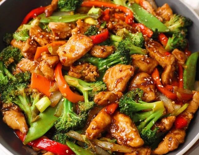 Chicken stir fry with vegetables in a wok, golden seared chicken pieces with bright bell peppers, broccoli florets, snap peas, glossy soy-ginger sauce, sesame seeds, scallions