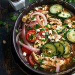 Chicken salad with vegetables in a white serving bowl, chunky shredded chicken mixed with diced celery, carrot, red bell pepper, red onion, all coated in creamy dressing, parsley and chives on top, served on butter lettuce leaves