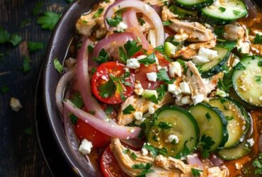 Chicken salad with vegetables in a white serving bowl, chunky shredded chicken mixed with diced celery, carrot, red bell pepper, red onion, all coated in creamy dressing, parsley and chives on top, served on butter lettuce leaves