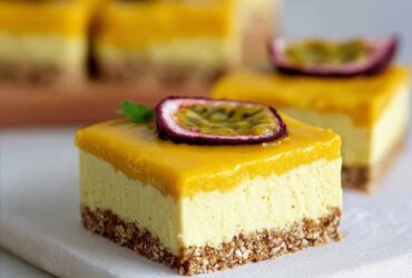 Passion fruit cheesecake bars stacked on a white marble board, golden graham cracker crust on the bottom, creamy white cheesecake layer in the middle, vibrant orange-yellow passion fruit topping with visible black seeds on top