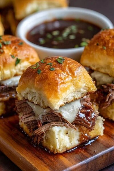 Beef brisket sliders on a wooden board, soft golden Hawaiian rolls split open and stuffed with juicy shredded smoked brisket, glossy BBQ sauce, creamy coleslaw with shredded cabbage and carrot, melted cheese, sesame seed buns topped with butter glaze