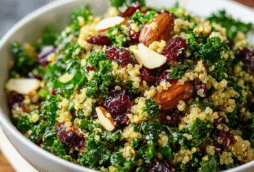 Quinoa kale salad in a ceramic bowl, fluffy tri-color quinoa with massaged green kale leaves, ruby red dried cranberries scattered, crumbled white feta cheese, golden almond slivers, lemony vinaigrette dressing