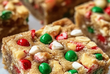 Holiday cookie bars cut into squares on parchment paper, soft buttery sugar cookie base with thick swirly cream cheese frosting layer on top, colorful red green and white festive sprinkles covering everything, cookie tin with more bars beside