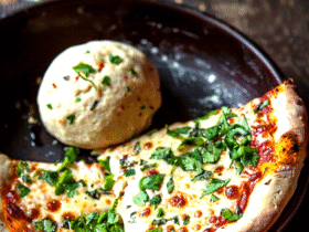 Classic homemade pizza overhead, golden crispy crust with charred bubbles, glossy red tomato sauce, melted bubbly mozzarella, fresh basil leaves scattered on top, dish fills the frame