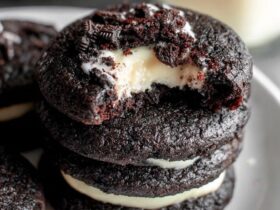 Black velvet cheesecake cookies on a black slate board, jet black cocoa cookies with white cream cheese centers oozing slightly, dramatic moody lighting, perfect for Halloween