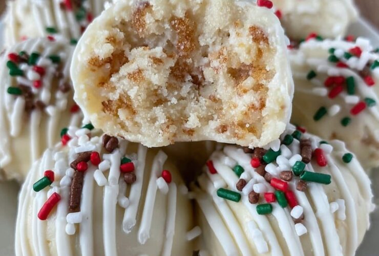 Sugar cookie truffles arranged on a white plate, white chocolate coated balls with red and green sprinkles, festive holiday styling, snowflake doily underneath