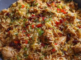 Turkey combo rice in a deep cast iron skillet, fluffy seasoned rice with ground turkey, diced bell peppers, corn, black beans, sprinkled with green onion and shredded cheese, fork lifting a bite