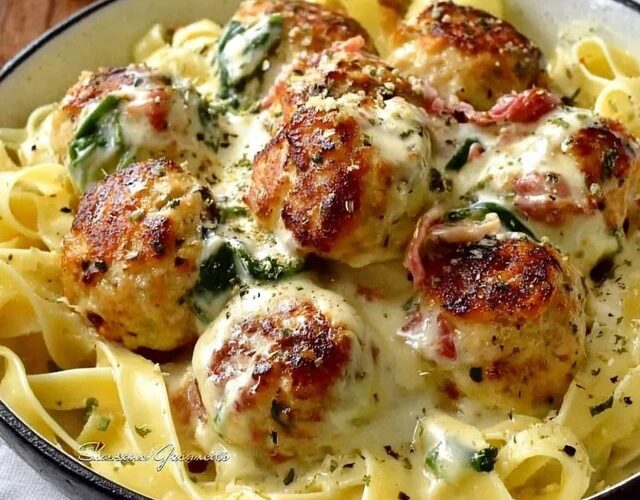 Creamy chicken meatball pasta in a deep skillet, golden chicken meatballs scattered through penne pasta, glossy cream sauce, fresh basil, parmesan grated on top, served with crusty bread on the side