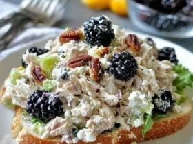 Chicken salad sandwich on toasted croissant, creamy chunky chicken salad with halved red grapes, celery and herbs spilling out, lettuce leaf, served with chips on the side