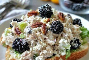Chicken salad sandwich on toasted croissant, creamy chunky chicken salad with halved red grapes, celery and herbs spilling out, lettuce leaf, served with chips on the side