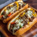 Philly cheesesteak sandwich on a hoagie roll overflowing with thinly sliced steak, sautéed peppers and onions, and gooey melted provolone cheese