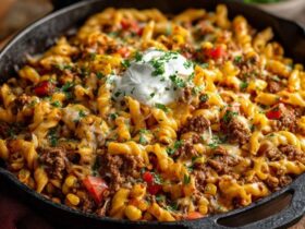 Cheesy beef pasta skillet, short pasta and ground beef in a creamy tomato sauce topped with melted cheese and parsley, served in a cast iron pan