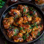 Honey butter chicken overhead, golden crispy chicken pieces coated in glossy sticky honey butter glaze, sesame seeds and fresh chopped parsley scattered, dish fills the frame, warm golden tones