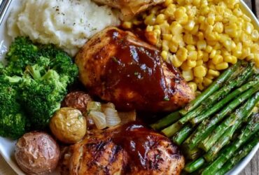 Grilled chicken dinner plate, juicy grill-marked chicken breast with roasted potatoes, grilled vegetables and a lemon wedge, garnished with fresh herbs