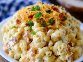 Cheesy bacon macaroni salad in a bowl, elbow macaroni in a creamy dressing with cubes of cheddar, crispy bacon bits, diced celery and red onion, sprinkle of chives